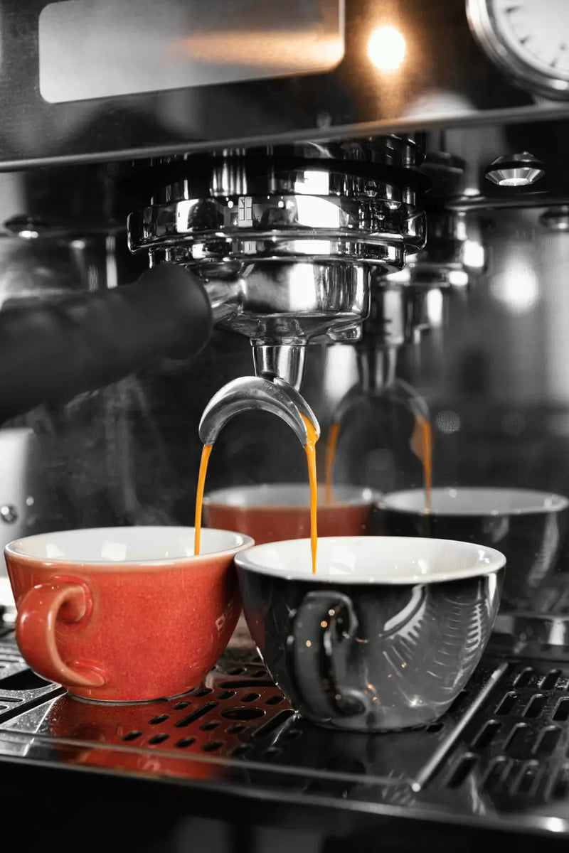 Close-up of an espresso machine brewing coffee into two cups